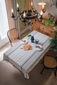 Détail d'une nappe bohème en coton et lin avec motifs géométriques noirs et franges