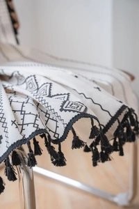 Detail of bohemian cotton linen fabric with black geometric print and manual tassels