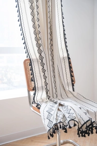 Detail of bohemian cotton linen curtain with black geometric patterns and fringe