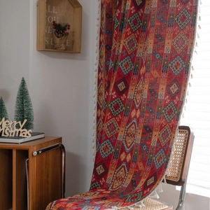 Ethnic geometric tapestry with tassels and red festive pattern on a rattan chair