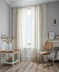 Detail of bohemian cotton linen curtain with green geometric prints and white tassels