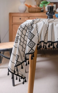 Détail d'une nappe bohème en coton et lin avec imprimé géométrique et pompons noirs
