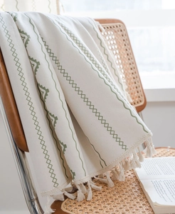 Detail of bohemian cotton linen fabric with green geometric embroidery and tassels