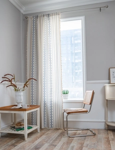 Detail of blue geometric patterns and fringe tassels on a bohemian style window curtain