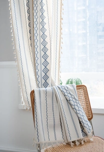 Detail of bohemian curtain featuring blue geometric patterns and decorative edge tassels