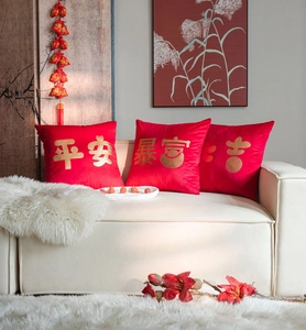 Three red velvet pillow covers with gold festive Chinese characters on white sofa