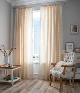 Detailed shot of bohemian cotton linen curtains with yellow diamond patterns and fringe trim
