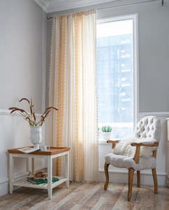 Detail of bohemian curtain with yellow geometric diamond pattern and white ball tassels
