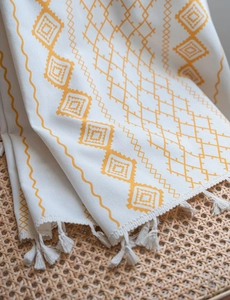 Detail of bohemian cotton linen fabric with orange geometric patterns and white tassels