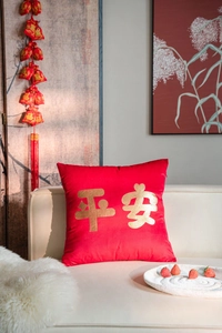 Detail of red velvet cushion cover featuring gold foil Ping An text on a white sofa