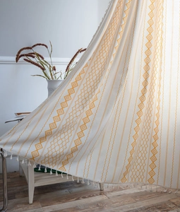 Detail of bohemian geometric print curtain with soft white handmade tassels texture