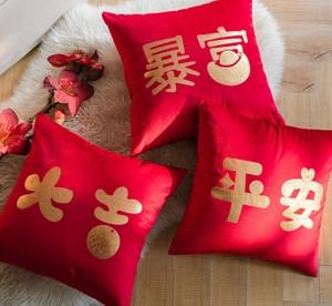 Close-up of three red velvet cushion covers with gold foil Chinese characters on white rug