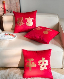 Detail of red velvet pillow cover with gold foil Chinese characters on beige sofa