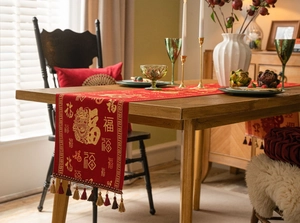 Detail of red festive table runner with gold embroidery dragon pattern and colorful tassels