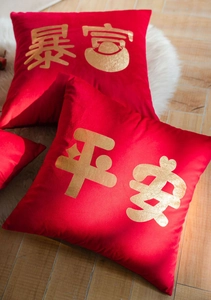 Detail of red velvet pillow cover featuring golden foil calligraphy for New Year decor
