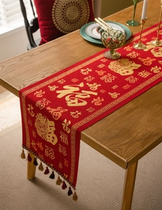 Detail of red festive table runner with golden Fu characters, jacquard fabric, and tassels