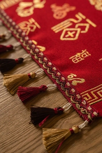 Detailed close-up of red Chinese New Year table runner with gold Fu character and silk tassels