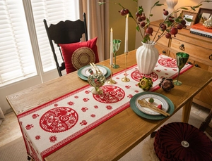 Detail of white jacquard table runner with red festive embroidery and tassels