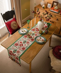 Top view of floral table runner with red tassels on a vintage dining table set
