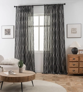 Detail of black bohemian curtain featuring white wave patterns and decorative tassels