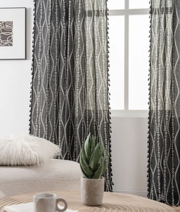 Detail of black semi-sheer curtain with white floral patterns and elegant tassel fringe