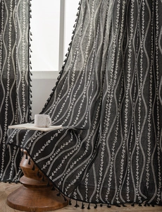 Close-up of black linen texture curtain with white floral print and tassel edges