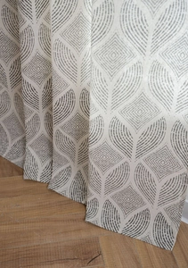 Détail de rideaux en lin-coton à motifs géométriques montrant la texture sur sol en bois