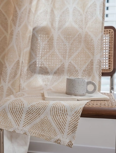 Gros plan détaillé du rideau crème aux motifs géométriques de feuilles sur chaise bois