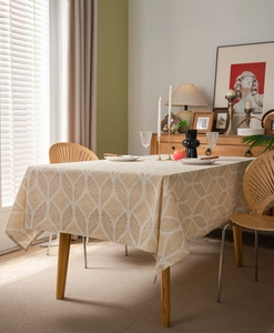 Detailed view of beige geometric pattern linen tablecloth on a wooden dining table