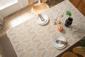 Detail of linen tablecloth with geometric leaf patterns in a cozy dining setting