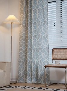 Détail de rideaux aux motifs géométriques bleus et blancs dans un salon de style nordique