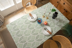 Detail view of cotton linen tablecloth with green geometric leaf pattern and neat stitching