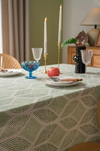 Detail view of cotton linen tablecloth with green geometric patterns on a dining table