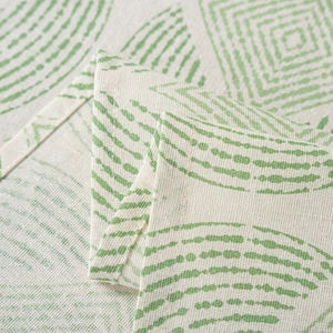Detailed macro view of the cream linen tablecloth with green geometric print and stitched edges