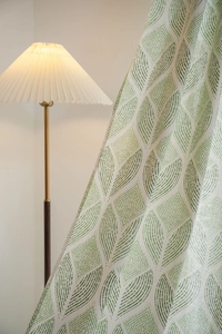 Détail de l'imprimé géométrique de feuilles sur rideau occultant avec lampadaire chaleureux