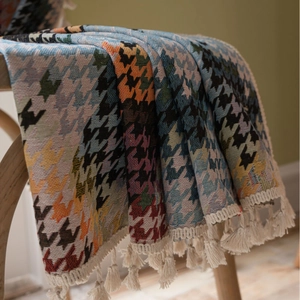 Kleurrijke pied-de-poule jacquard deken met katoenen kwastjes op een houten stoel