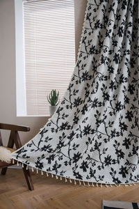 Dettaglio della tenda in lino con motivo floreale nero e bordo con nappe decorative bianche