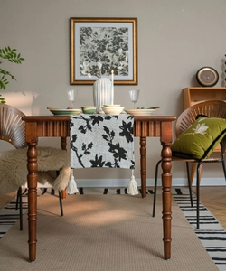 Detail of black and white floral table runner with woven texture on a wooden dining table