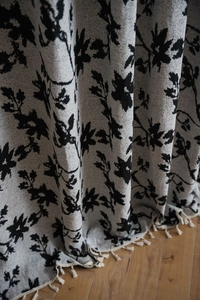 Dettaglio della tenda jacquard con motivo di foglie nere e bordo con nappine boho