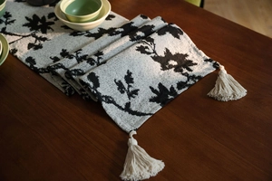 Macro shot of Nordic jacquard table runner with leaf patterns and elegant corner tassels