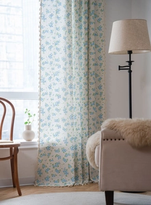Détail du rideau à fleurs bleues avec des franges décoratives en tissu de coton et lin