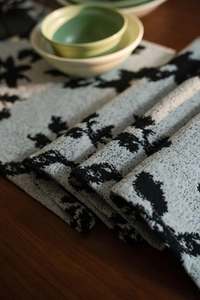 Close-up of black and white floral jacquard table runner fabric with tassel details
