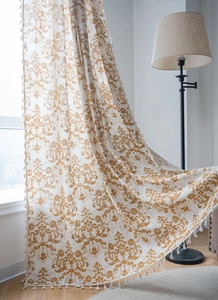 Detail of vintage damask floral pattern and hanging tassels on khaki linen curtains