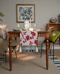 Close-up of Nordic jacquard table runner with red floral patterns and elegant cream tassels