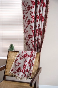 Dettaglio di tende jacquard floreali rosse con eleganti bordi a frange con nappe in crema