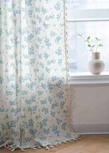 Vue détaillée du motif floral bleu sur rideaux en lin avec glands décoratifs