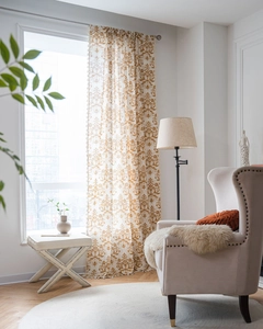 Detail of cream damascus curtains with golden patterns and elegant tassels in home setting