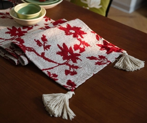 Close-up of jacquard table runner featuring red floral patterns and elegant white tassels