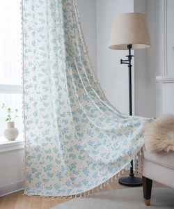Détail du rideau à fleurs bleues avec pompons blancs et texture semi-transparente élégante