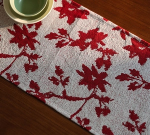 Detail of Nordic jacquard table runner with red floral motifs and elegant tassels